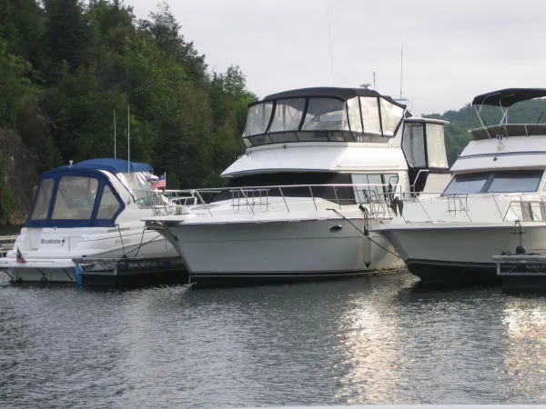 The Image of 1990 Carver 3608 Aft Cabin Motor Yacht docked among other boats on a calm lake. - 0