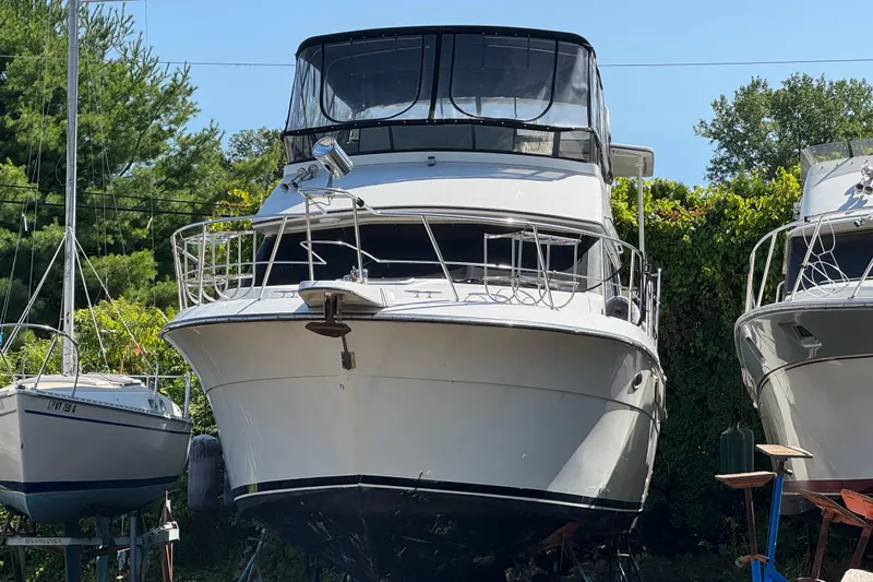 Slide: The Image of 1990 Carver 3608 Aft Cabin yacht on dry dock, surrounded by greenery. - 22