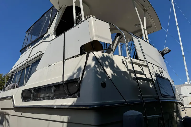 Slide: The Image of 1990 Carver 3608 Aft Cabin yacht with white exterior, docked under clear blue sky. - 5