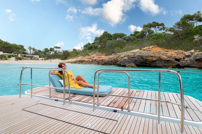 Slide: The Image of Woman relaxing on Lagoon 55 yacht deck, 2026 model, near scenic coastline. - 7