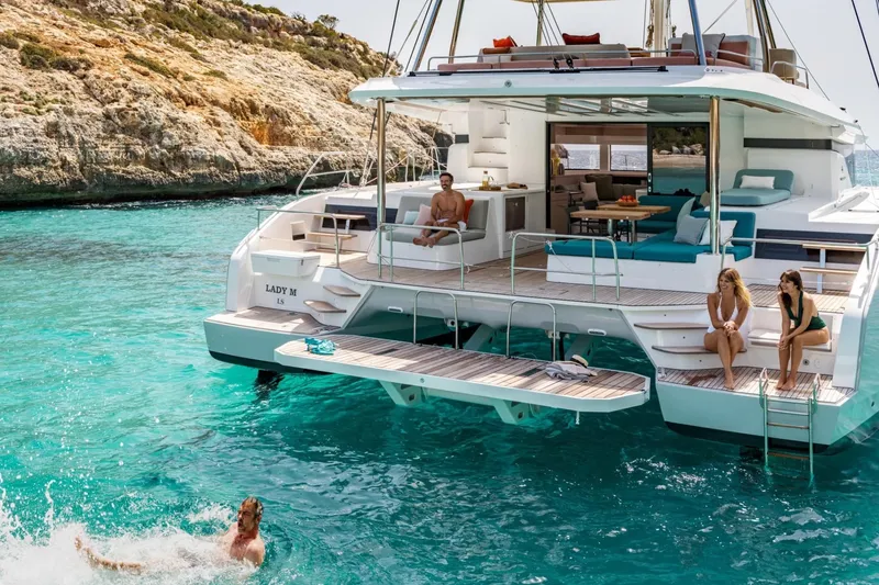 Slide: The Image of Luxurious 2026 Lagoon 55 yacht with people enjoying turquoise waters and sunbathing on deck. - 9