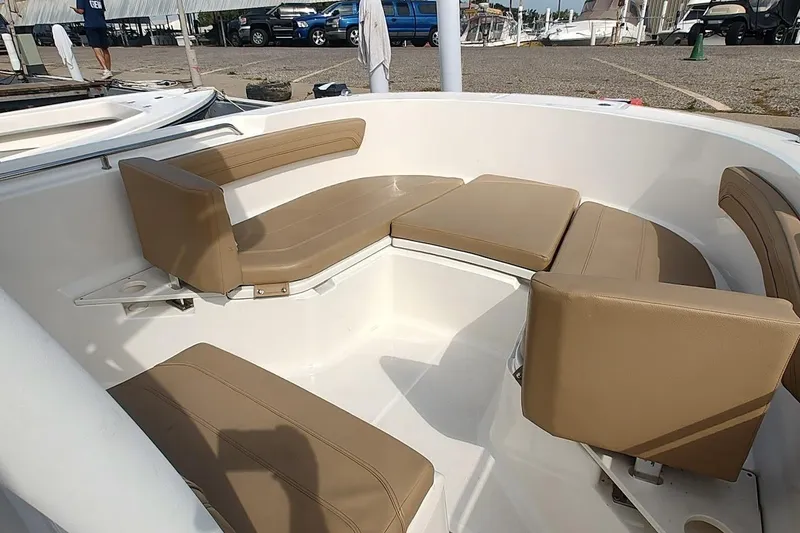 Slide: The Image of 2024 Bayliner Trophy T24CC boat interior with tan cushioned seating in a marina setting. - 18