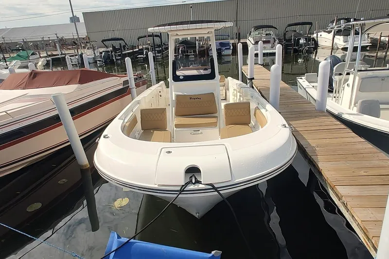 Slide: The Image of 2024 Bayliner Trophy T24CC boat docked at a marina, showcasing sleek design and spacious seating. - 2