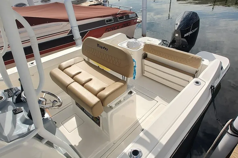 Slide: The Image of 2024 Bayliner Trophy T24CC boat interior with tan seating and Mercury outboard motor. - 5