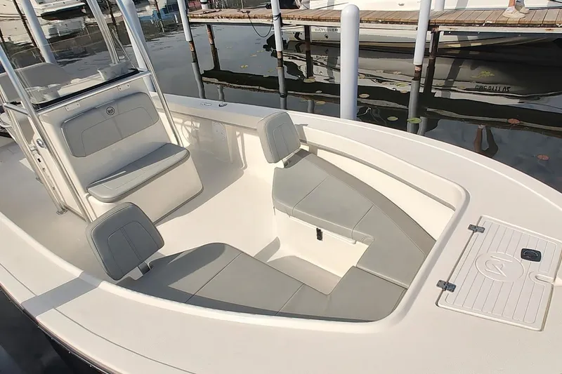 Slide: The Image of 2024 May-Craft 23 Cape Classic boat interior with seating and storage at a marina. - 10