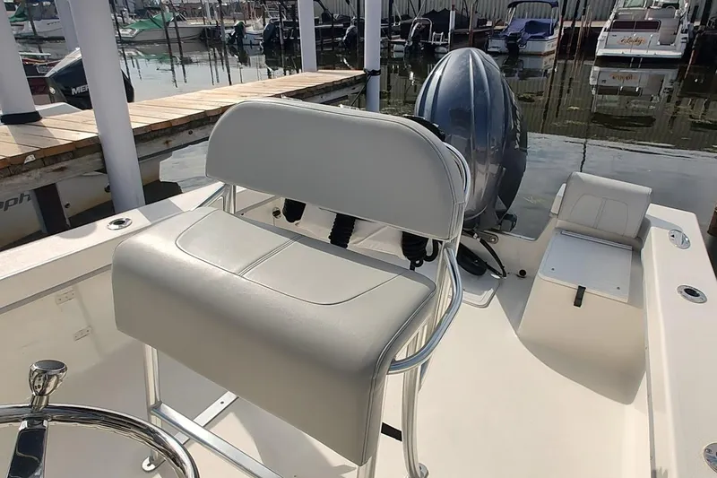 Slide: The Image of 2024 May-Craft 23 Cape Classic boat interior with seating and motor at a marina. - 12