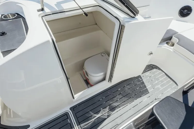 Slide: The Image of Manufacturer Provided Image: 2025 Bayliner VR6 Bowrider OB boat interior with open storage compartment and portable toilet. - 11