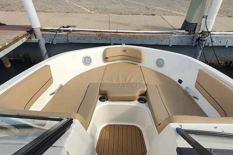 Slide: The Image of 2025 Bayliner VR6 Bowrider OB interior with tan seating and cup holders at dock. - 4
