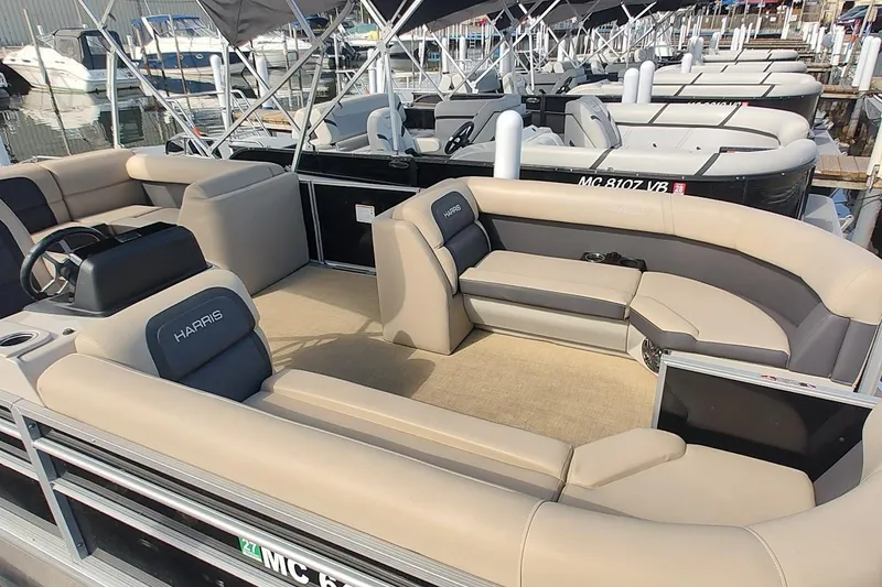 Slide: The Image of 2024 Harris Cruiser 230 pontoon boat with spacious seating at a marina. - 10