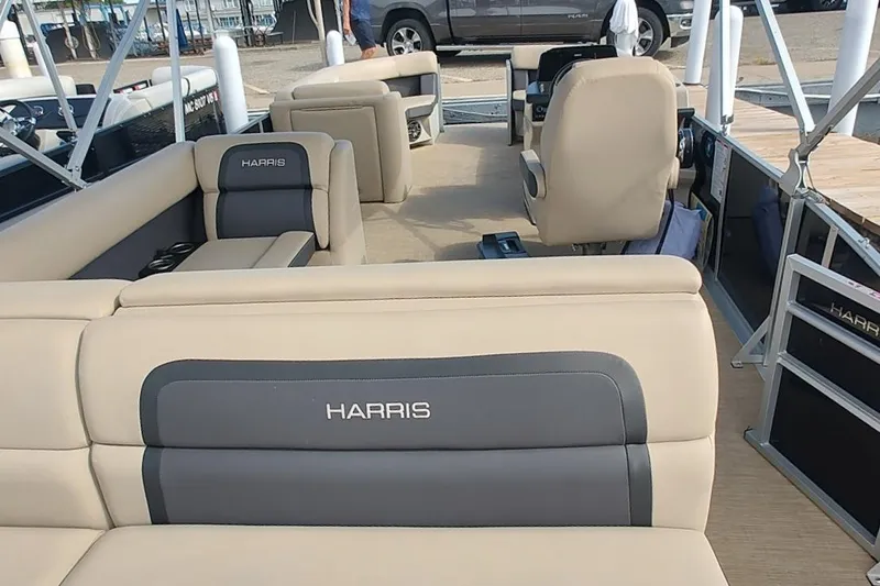 Slide: The Image of 2024 Harris Cruiser 230 pontoon boat interior with beige seating and steering console. - 4