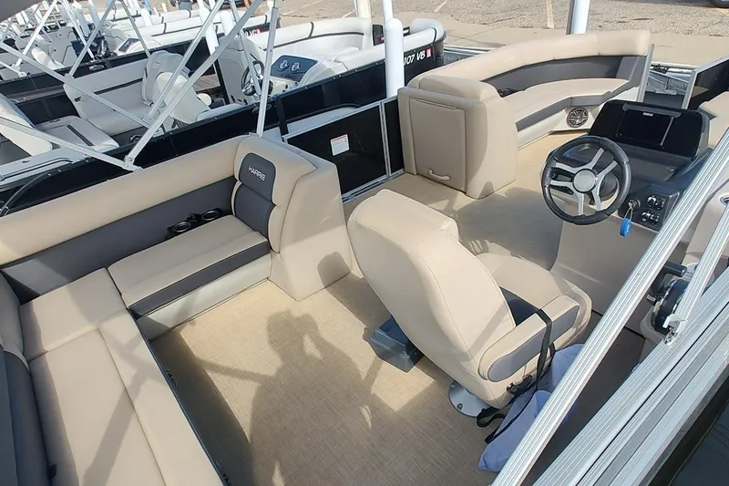 Slide: The Image of 2024 Harris Cruiser 230 pontoon boat interior with beige seating and steering console. - 7