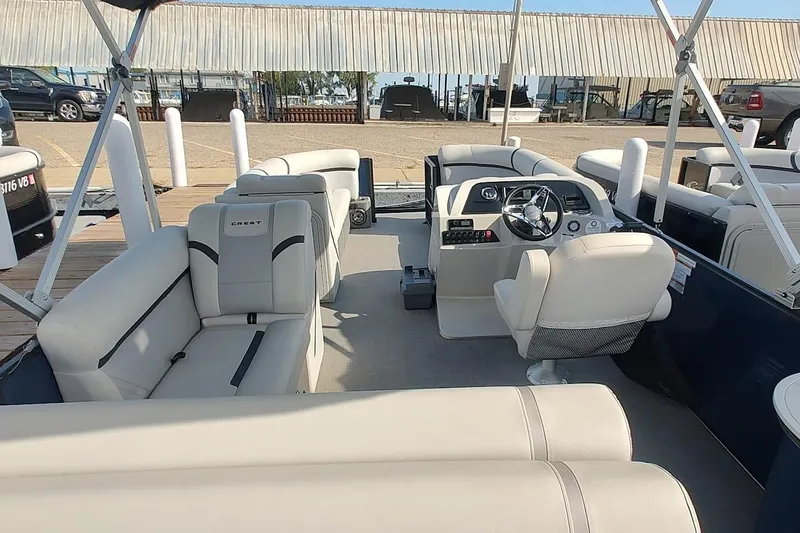 Slide: The Image of 2023 Crest Classic LX 220 pontoon boat interior with plush seating and modern helm. - 8