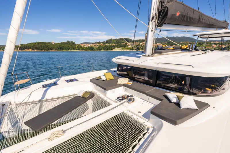 Slide: The Image of Luxurious 2026 Lagoon 43 catamaran with sunbathing area, sailing on serene blue waters. - 2