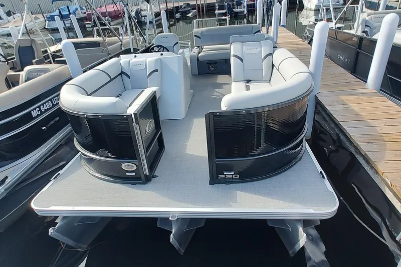 Slide: The Image of 2023 Crest Classic LX 220 pontoon boat with spacious seating at a marina dock. - 5
