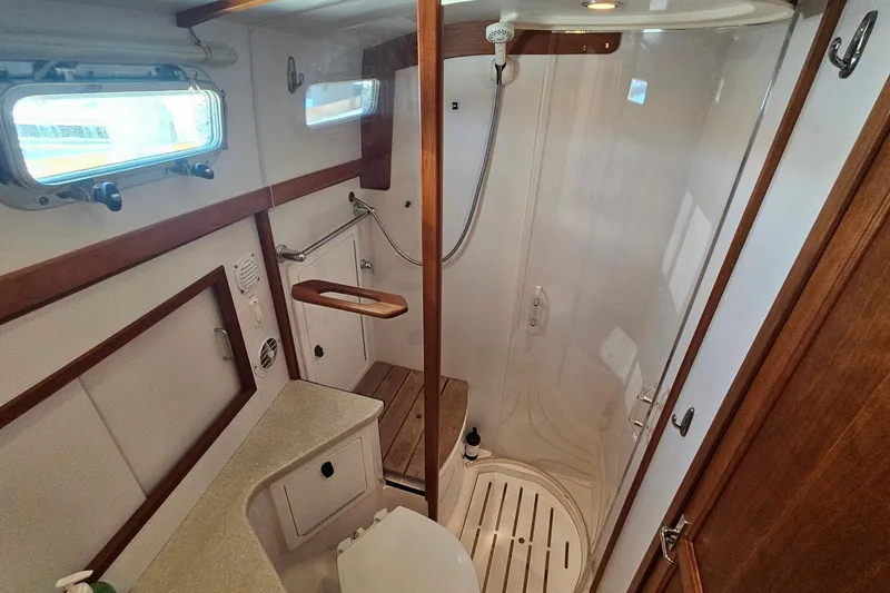Slide: The Image of 2009 Sabre 42 Express yacht interior with wooden table, cushioned seating, and plaid pillows. - 39