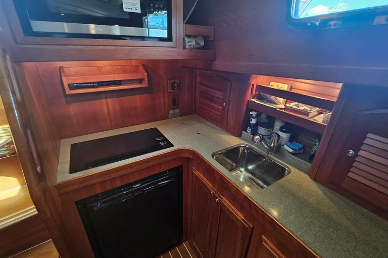 Slide: The Image of 2009 Sabre 42 Express yacht kitchen with stove, sink, and wooden cabinetry. - 56