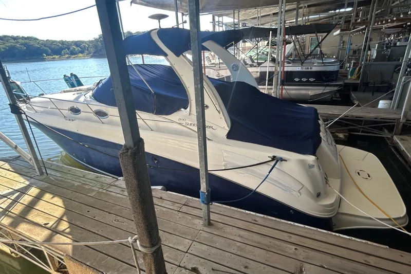 Slide: The Image of 2005 Sea Ray 300 Sundancer boat interior with seating and helm, docked by the water. - 17