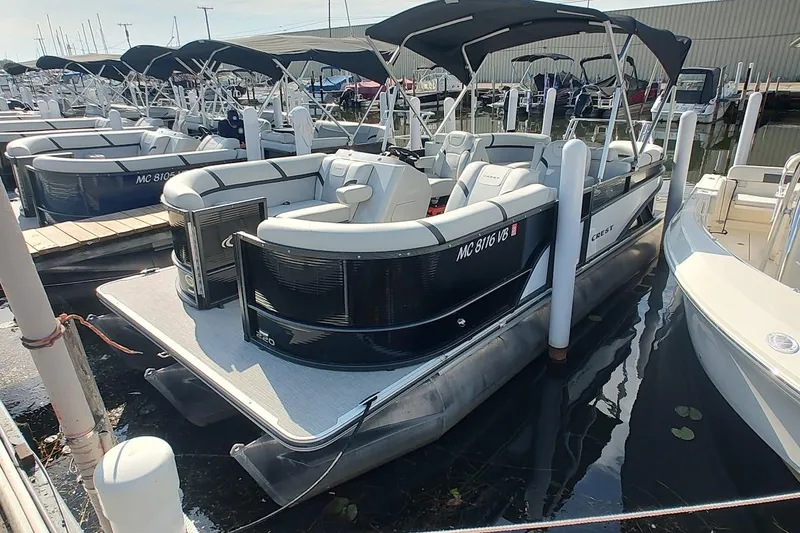 The Image of 2024 Crest Classic LX 220 pontoon boat docked at marina, featuring sleek design and spacious seating. - 0