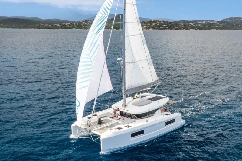 The Image of 2026 Lagoon 38 catamaran sailing on open sea with passengers relaxing on deck. - 0