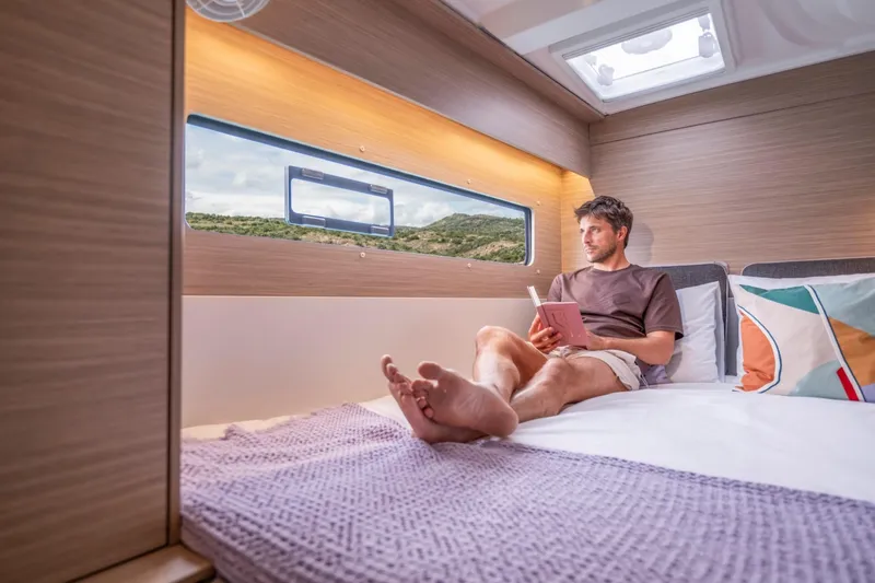 Slide: The Image of Man relaxing in 2026 Lagoon 38 cabin, reading a book by a scenic window. - 12