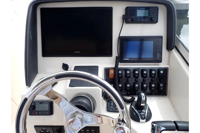 Slide: The Image of 2021 Grady-White Freedom 275 boat dashboard with steering wheel and electronic controls. - 15