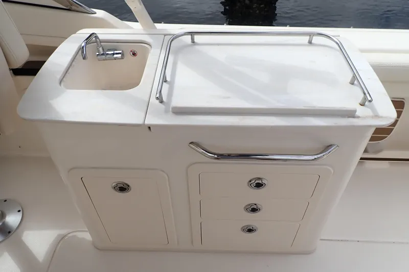 Slide: The Image of 2021 Grady-White Freedom 275 boat sink and storage area with stainless steel fixtures. - 26