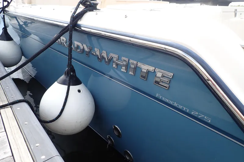 Slide: The Image of 2021 Grady-White Freedom 275 boat docked with fenders, showcasing sleek design. - 4
