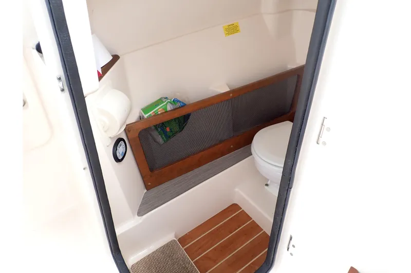Slide: The Image of 2021 Grady-White Freedom 275 boat interior with compact bathroom and wooden flooring. - 44