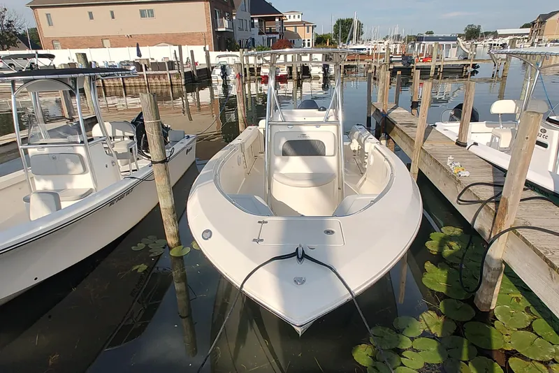 The Image of 2023 Cobia 237 Center Console boat docked at a marina with lily pads nearby. - 0