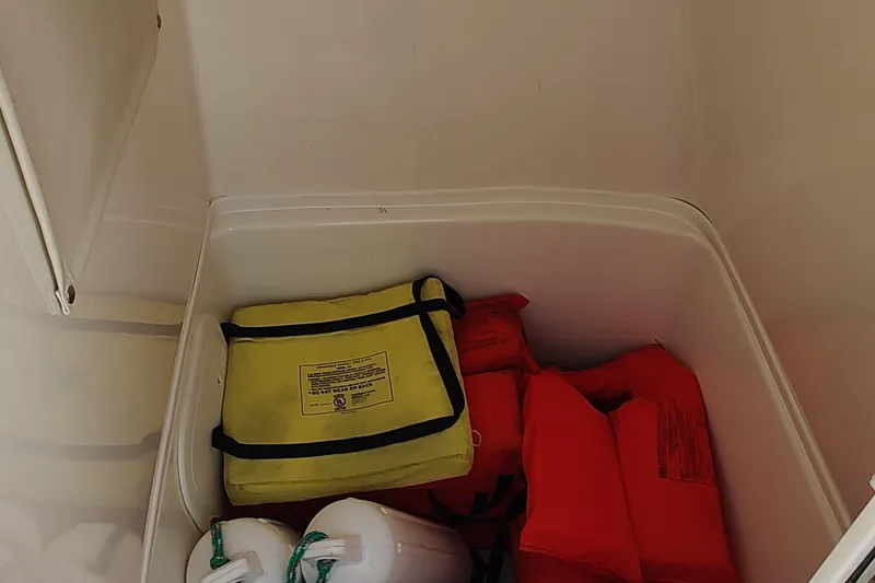 Slide: The Image of Storage compartment in 2023 Cobia 237 Center Console with life jackets and safety gear. - 10