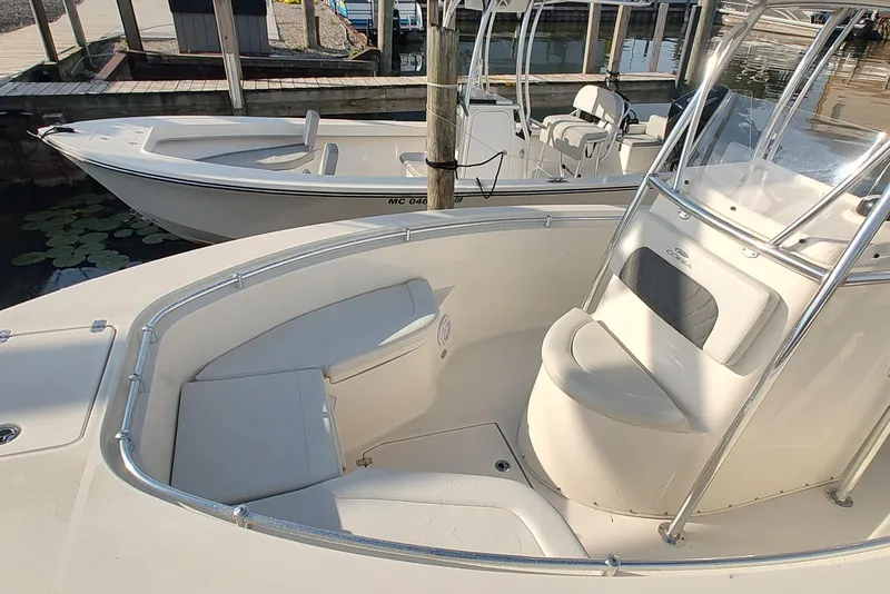 Slide: The Image of 2023 Cobia 237 Center Console boat with seating, docked near another vessel. - 3