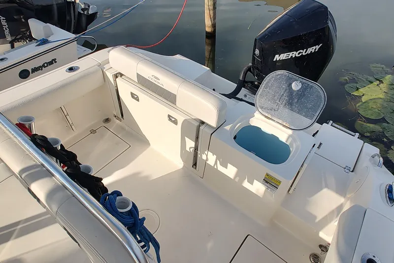 Slide: The Image of 2023 Cobia 237 Center Console boat interior with Mercury engine and open storage compartment. - 7
