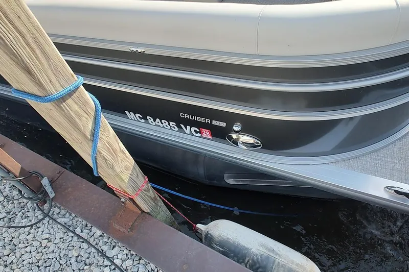 Slide: The Image of 2024 Harris Cruiser 230 pontoon boat docked with visible registration number. - 2