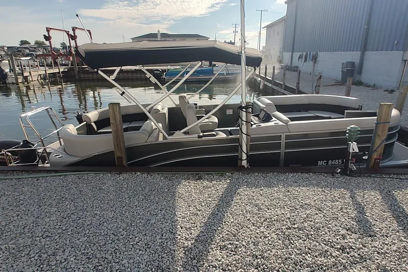 Slide: The Image of 2024 Harris Cruiser 230 pontoon boat docked at a marina, side view. - 3
