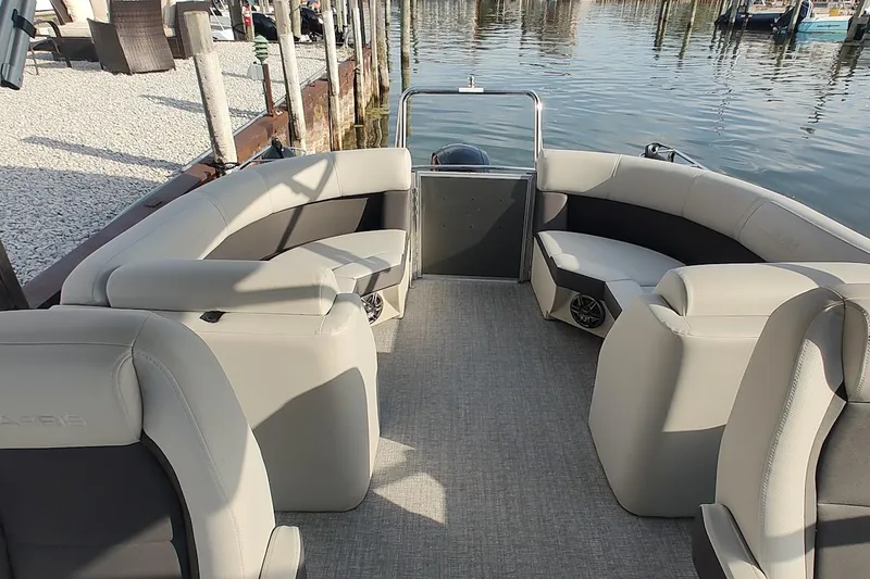Slide: The Image of 2024 Harris Cruiser 230 boat interior with plush seating, docked by the water. - 6
