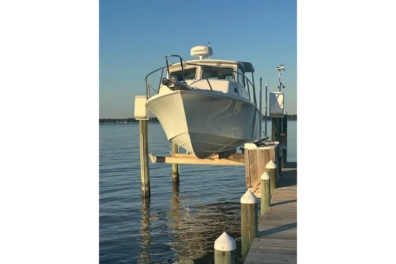 Slide: The Image of 2022 Parker 2520 XLD Sport Cabin boat on lift at dock, calm water background. - 1