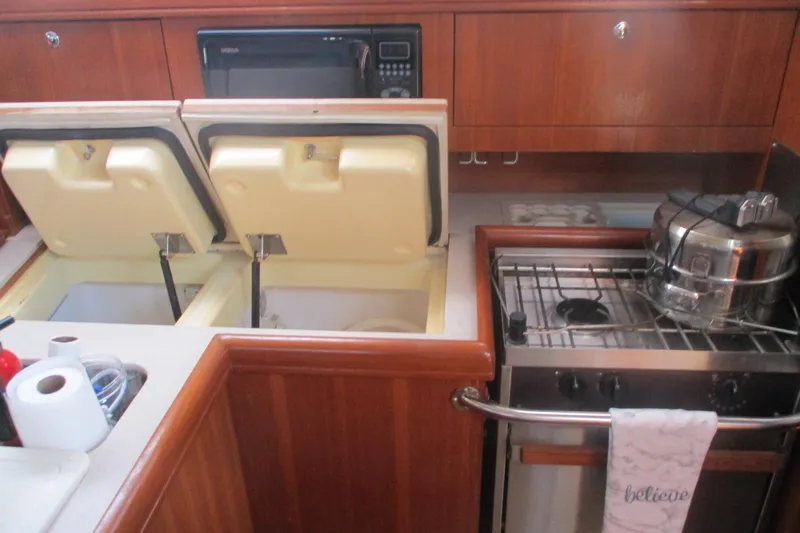 Slide: The Image of 2003 Hunter 356 yacht kitchen with stove, storage compartments, and wooden cabinetry. - 10