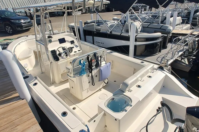 Slide: The Image of 2023 Cobia 237 Center Console boat at marina, featuring spacious deck and modern controls. - 10