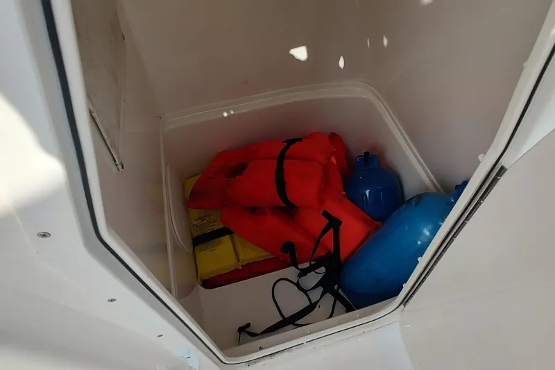 Slide: The Image of Storage compartment in 2023 Cobia 237 Center Console with life jackets and blue containers. - 15