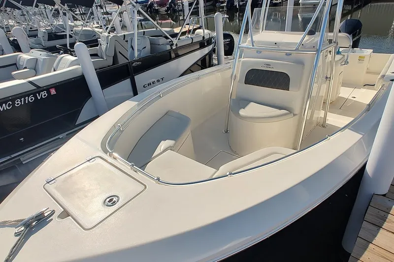 Slide: The Image of 2023 Cobia 237 Center Console boat with spacious seating and sleek design at a marina. - 2