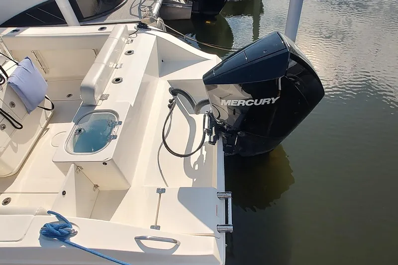 Slide: The Image of 2023 Cobia 237 Center Console boat with Mercury outboard engine, docked on calm water. - 4