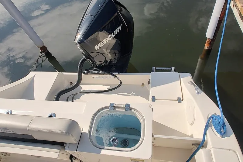 Slide: The Image of 2023 Cobia 237 Center Console boat with Mercury engine, docked by water. - 7