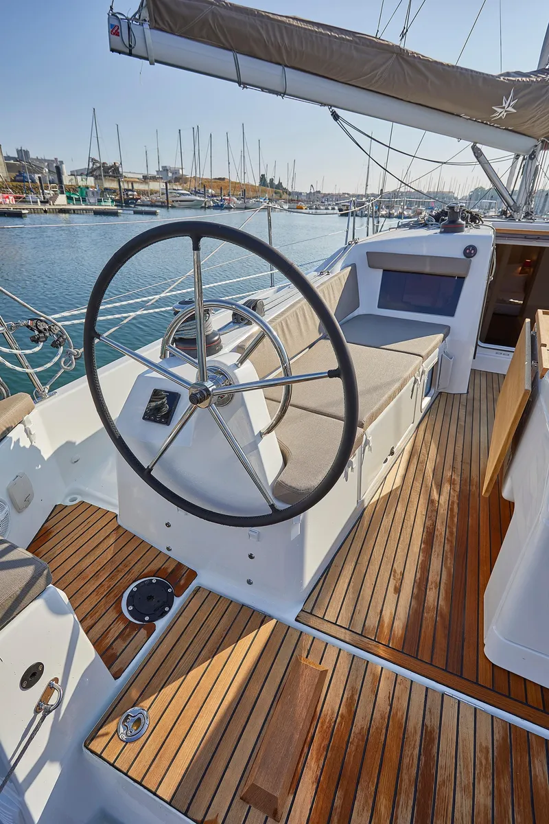 Slide: The Image of 2026 Jeanneau 410 sailboat cockpit with wooden deck and steering wheel, docked at marina. - 10