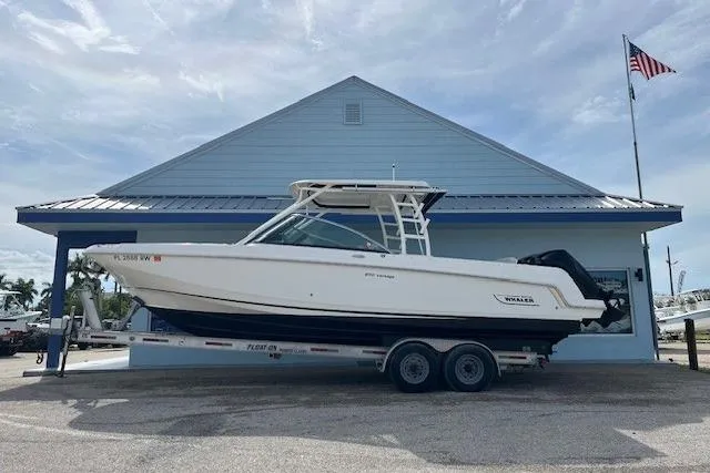 The Image of 2018 Boston Whaler 270 Vantage boat on trailer, parked outside a blue building. - 1