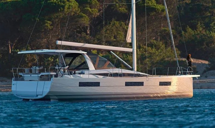 Slide: The Image of 2026 Jeanneau Yachts 60 sailing on calm waters near a forested shoreline. - 11