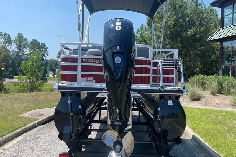 Slide: The Image of 2025 Ranger Reata 220FC pontoon boat with 150 HP engine, parked outdoors. - 4