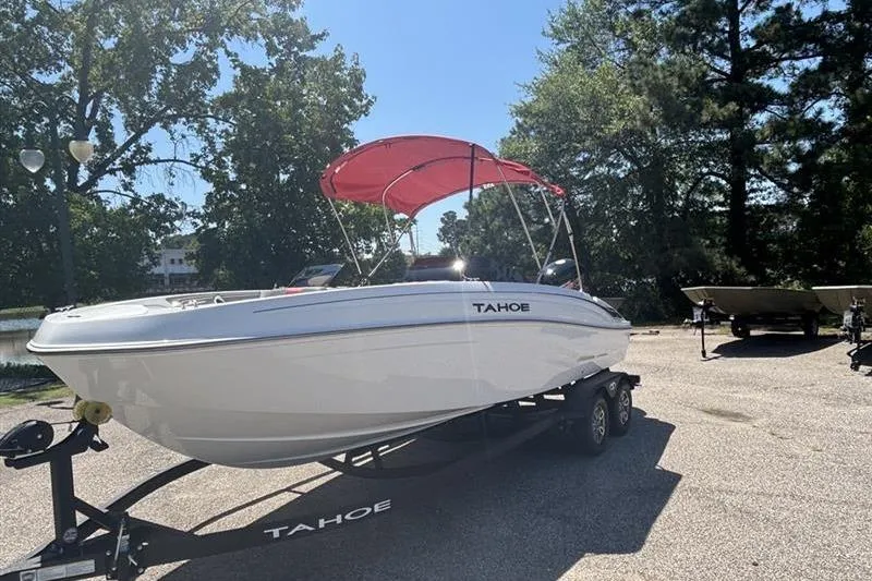 Slide: The Image of 2026 Tahoe T21 boat with red canopy on trailer, parked outdoors. - 2