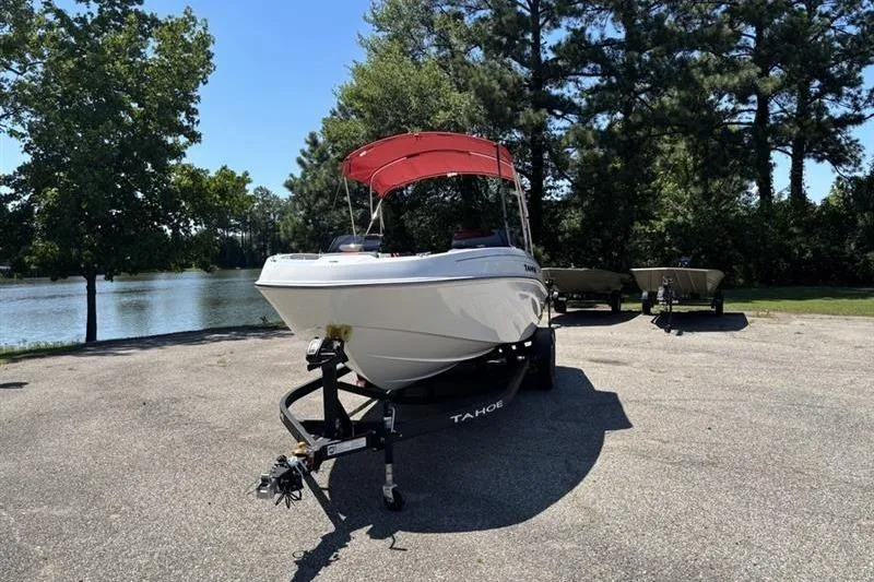 Slide: The Image of 2026 Tahoe T21 boat with red canopy on trailer by a lake. - 1
