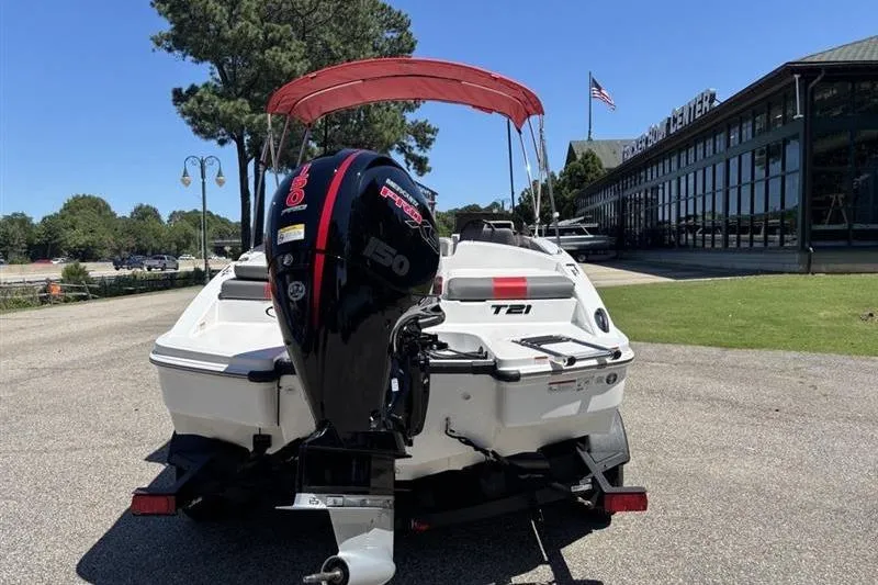 Slide: The Image of 2026 Tahoe T21 boat with outboard motor and red canopy, parked near a building. - 3