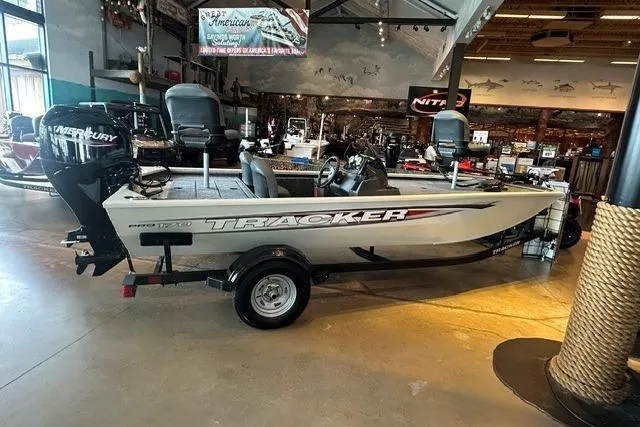 Slide: The Image of 2026 Tracker Pro 170 boat displayed indoors with Mercury engine. - 2